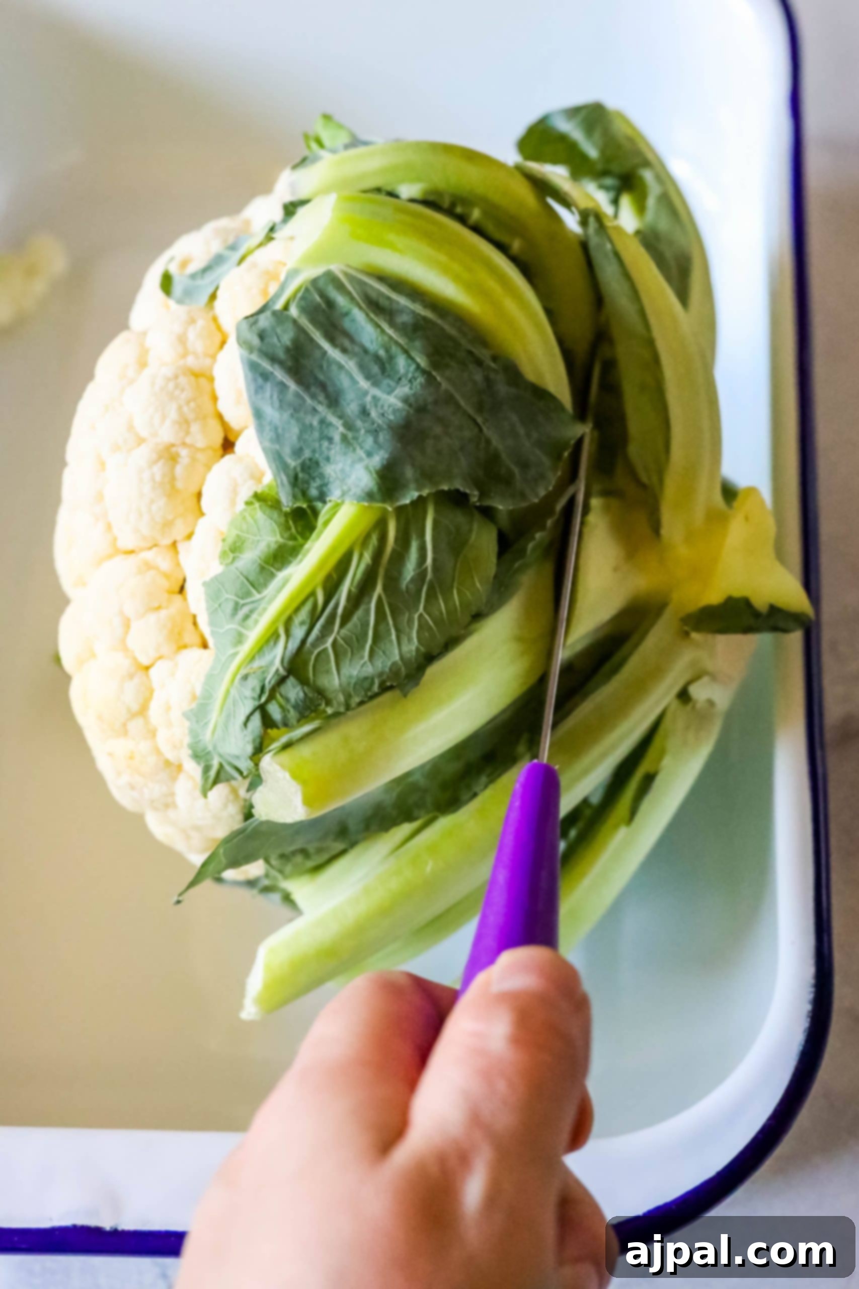 A person preparing an easy keto roasted cauliflower dish in a baking dish.