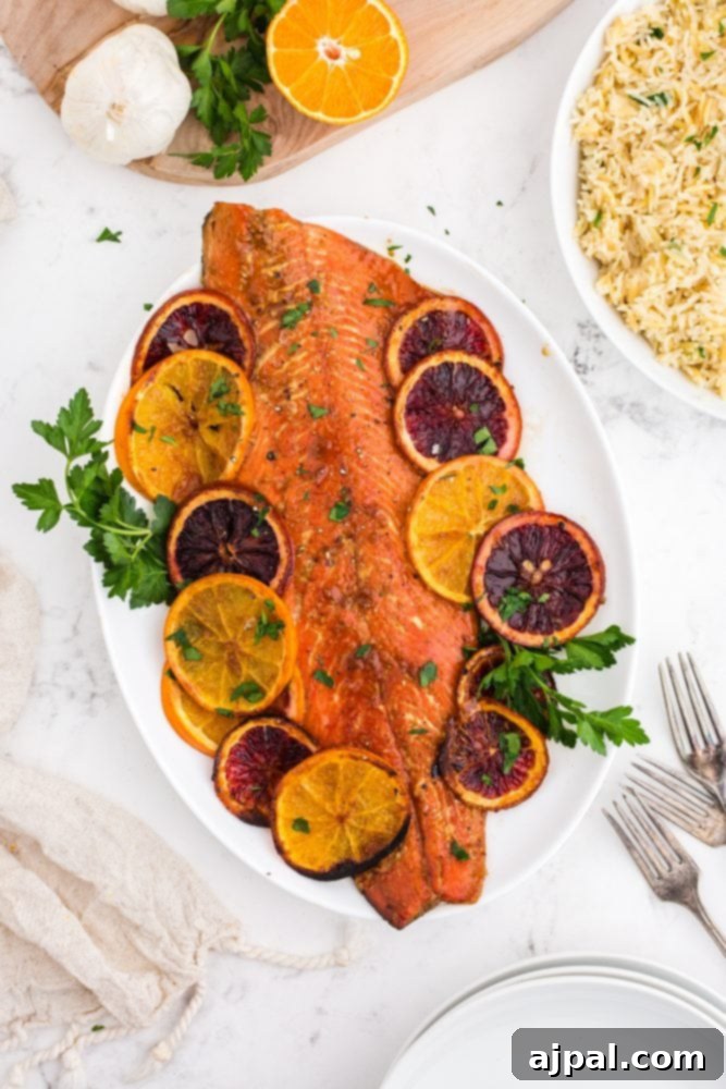 A close-up of a plate featuring baked salmon with orange slices, showcasing the vibrant colors and tender texture.