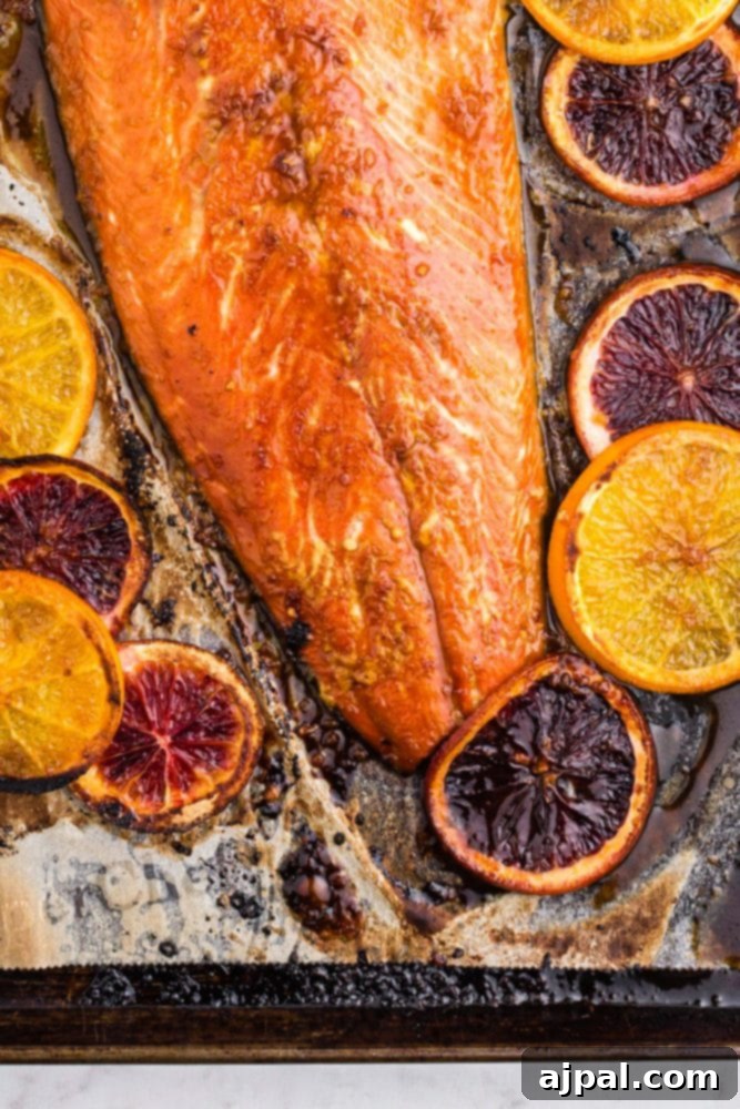 Close-up of baked salmon adorned with vibrant orange slices, showing the beautiful caramelization of the glaze.