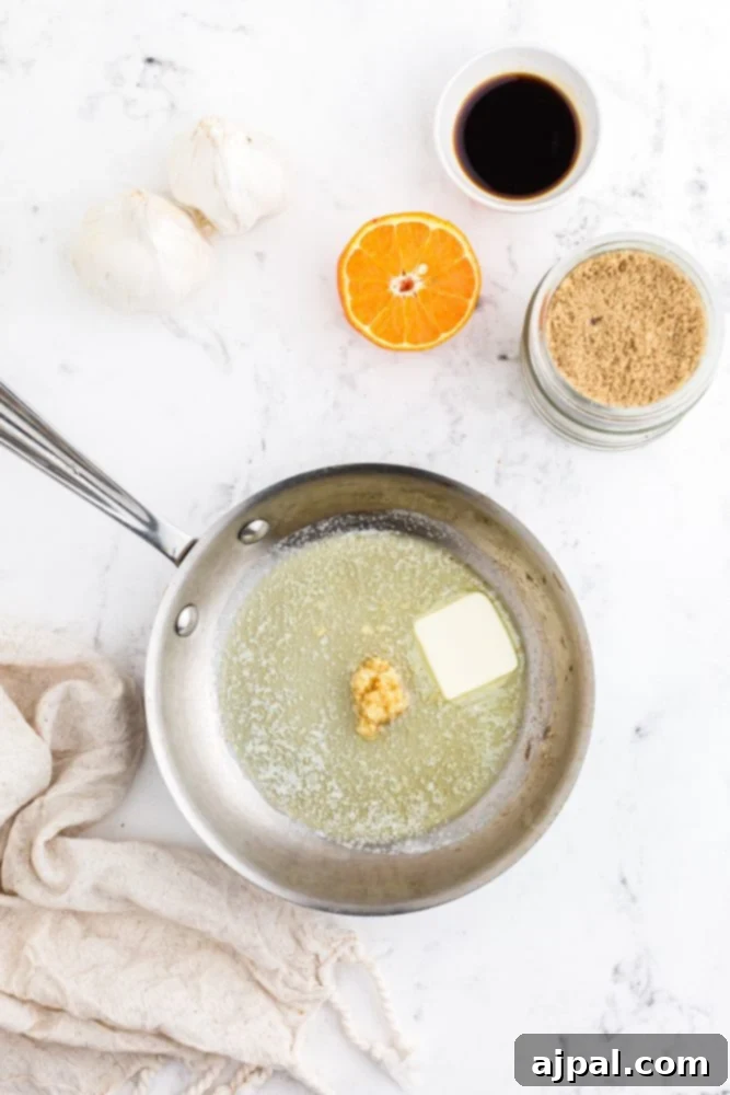 Melted butter and minced garlic simmering in a small pan, releasing a fragrant aroma as they cook.
