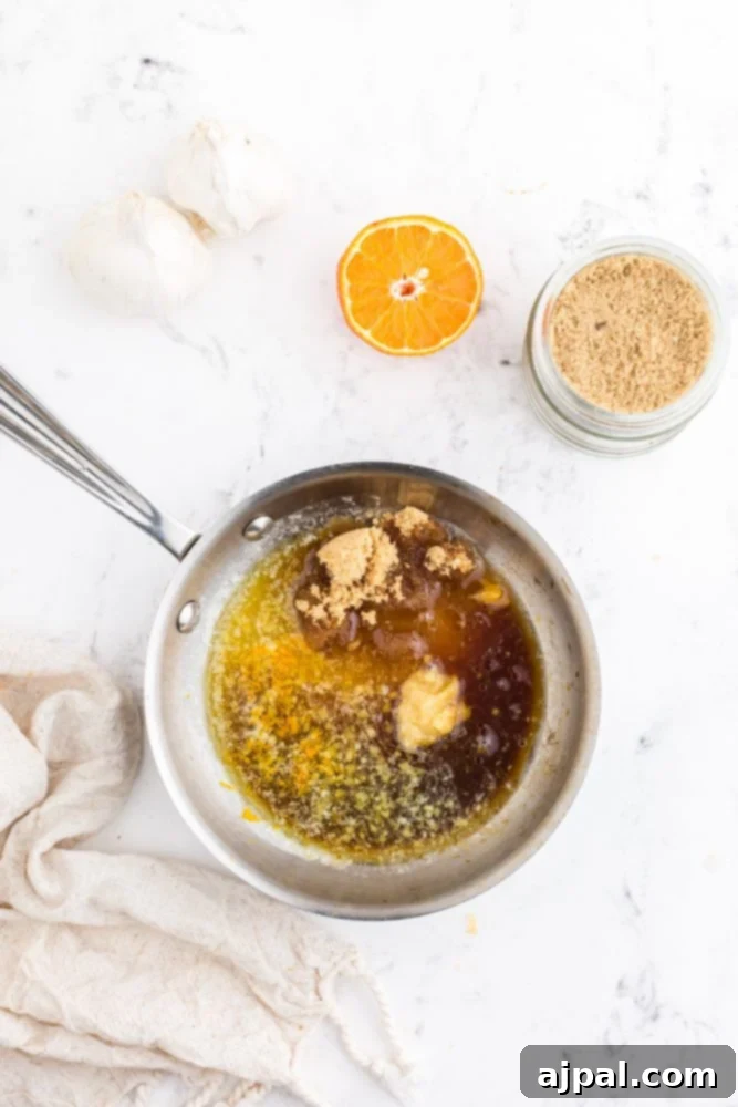 Ingredients for the orange glaze—orange juice, ginger, garlic, brown sugar, and soy sauce—combined and simmering in a pan.