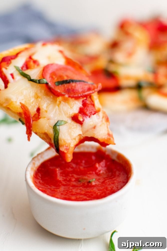 Whip Up Easy Keto Naan Pizzas 2 A slice of “keto naan pizza” is being dipped into a bowl of sauce.