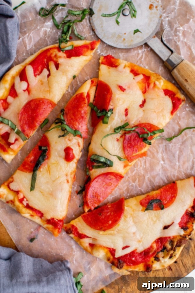 Whip Up Easy Keto Naan Pizzas 5 A slice of keto pepperoni pizza on a cutting board.