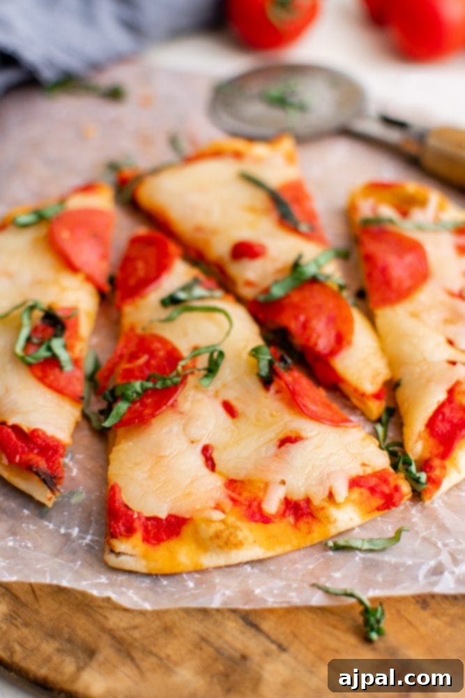 Whip Up Easy Keto Naan Pizzas 3 A keto-friendly naan pizza topped with tomatoes and basil on a cutting board.