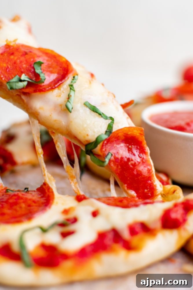 Whip Up Easy Keto Naan Pizzas 4 A slice of pepperoni pizza is being dipped in sauce at a naan pizza party.