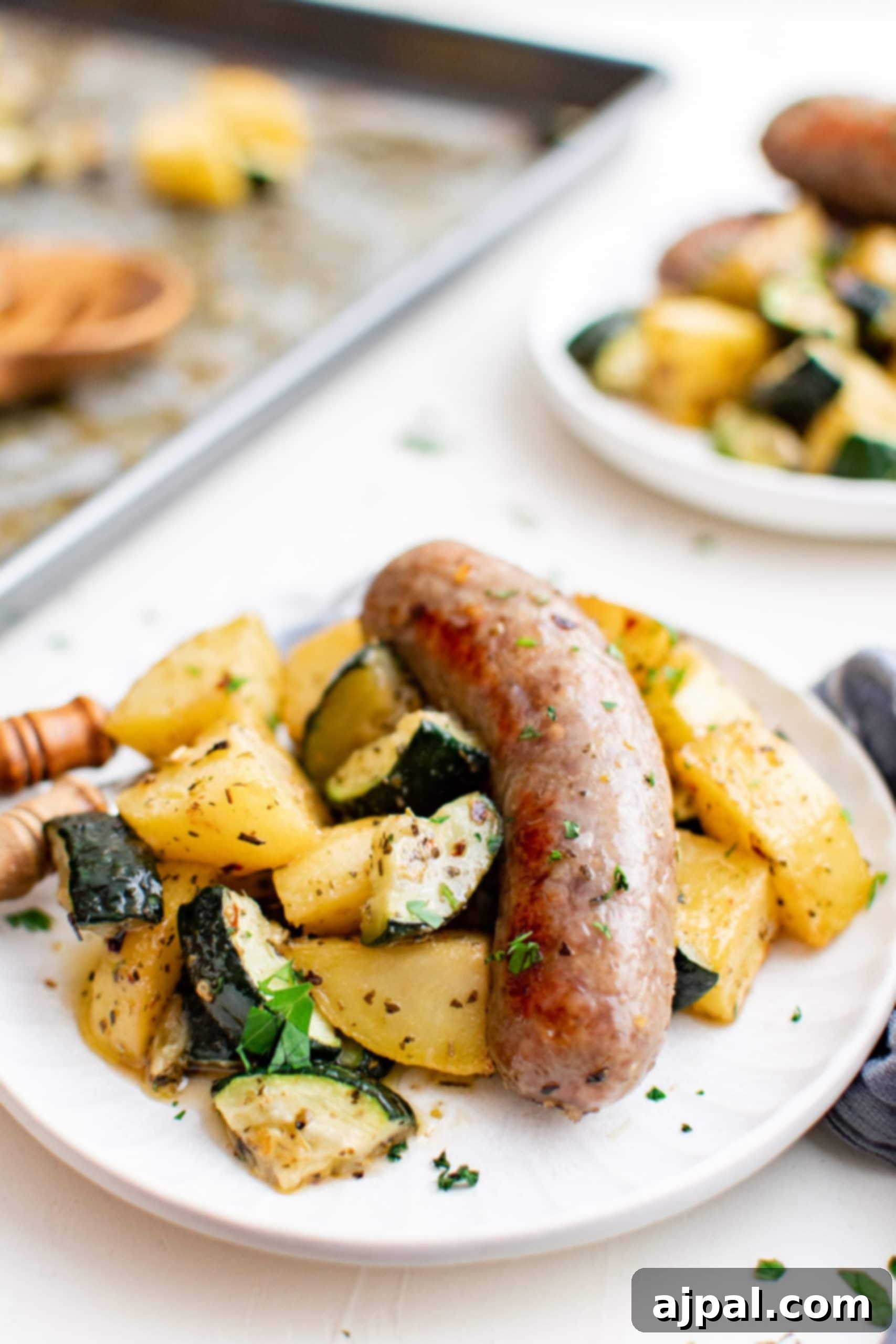 Simple Sheet Pan Sausage Dinner 8 Picture of sausage and assorted vegetables on a plate, featuring roasted zucchini and potatoes.