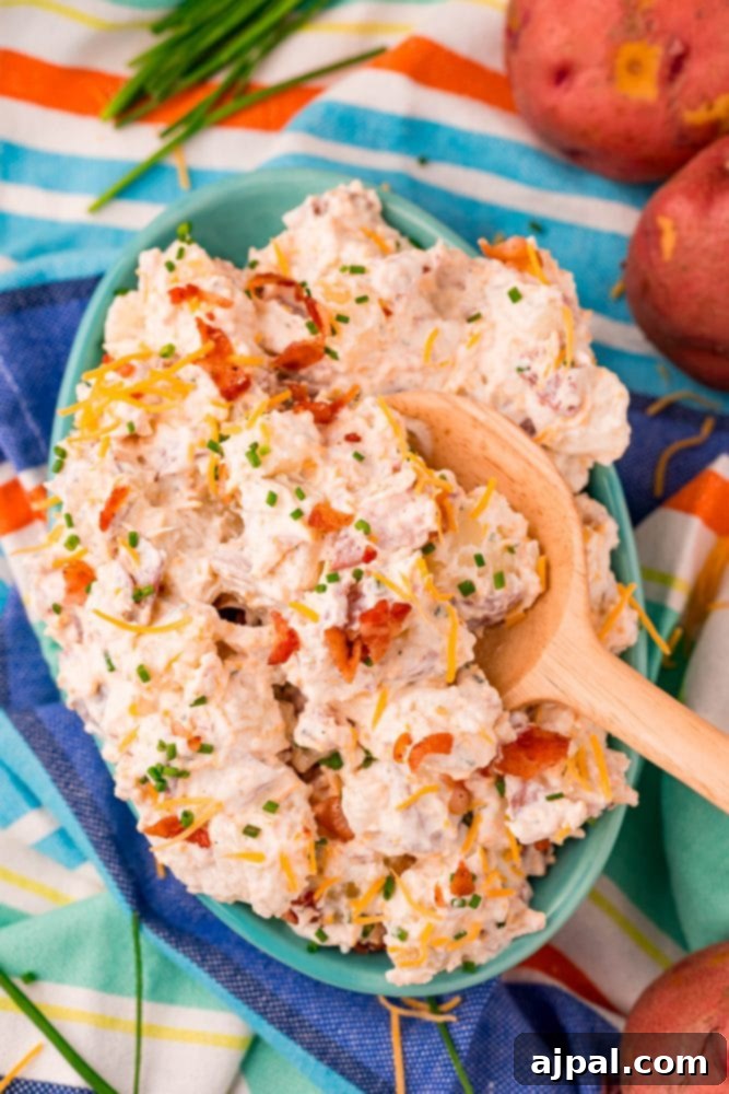 creamy ranch potato salad in a blue bowl on a colorful towel with a spoon in it