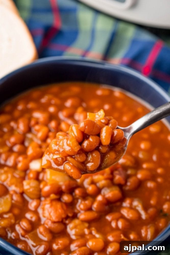 A close-up picture of rich, flavorful baked beans simmering in a slow cooker, ready to be served.