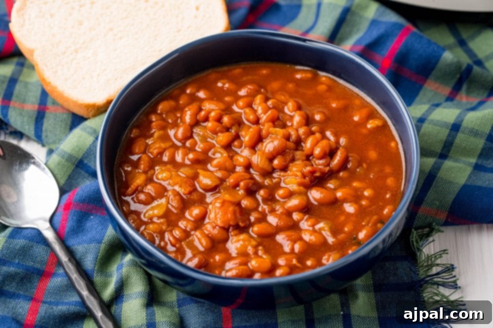 A beautifully presented bowl of slow cooker baked beans, perfect for a hearty meal, next to a slice of bread.
