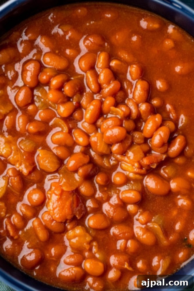 A vibrant blue bowl filled with the best slow cooker baked beans, a perfect side dish for any occasion.