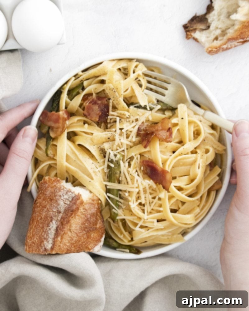 Asparagus Carbonara with Roasted Flair 2 A beautiful bowl of Roasted Asparagus Carbonara, featuring fettuccine pasta, vibrant green asparagus, crispy bacon bits, and a rich, creamy sauce, garnished with fresh herbs and grated cheese.