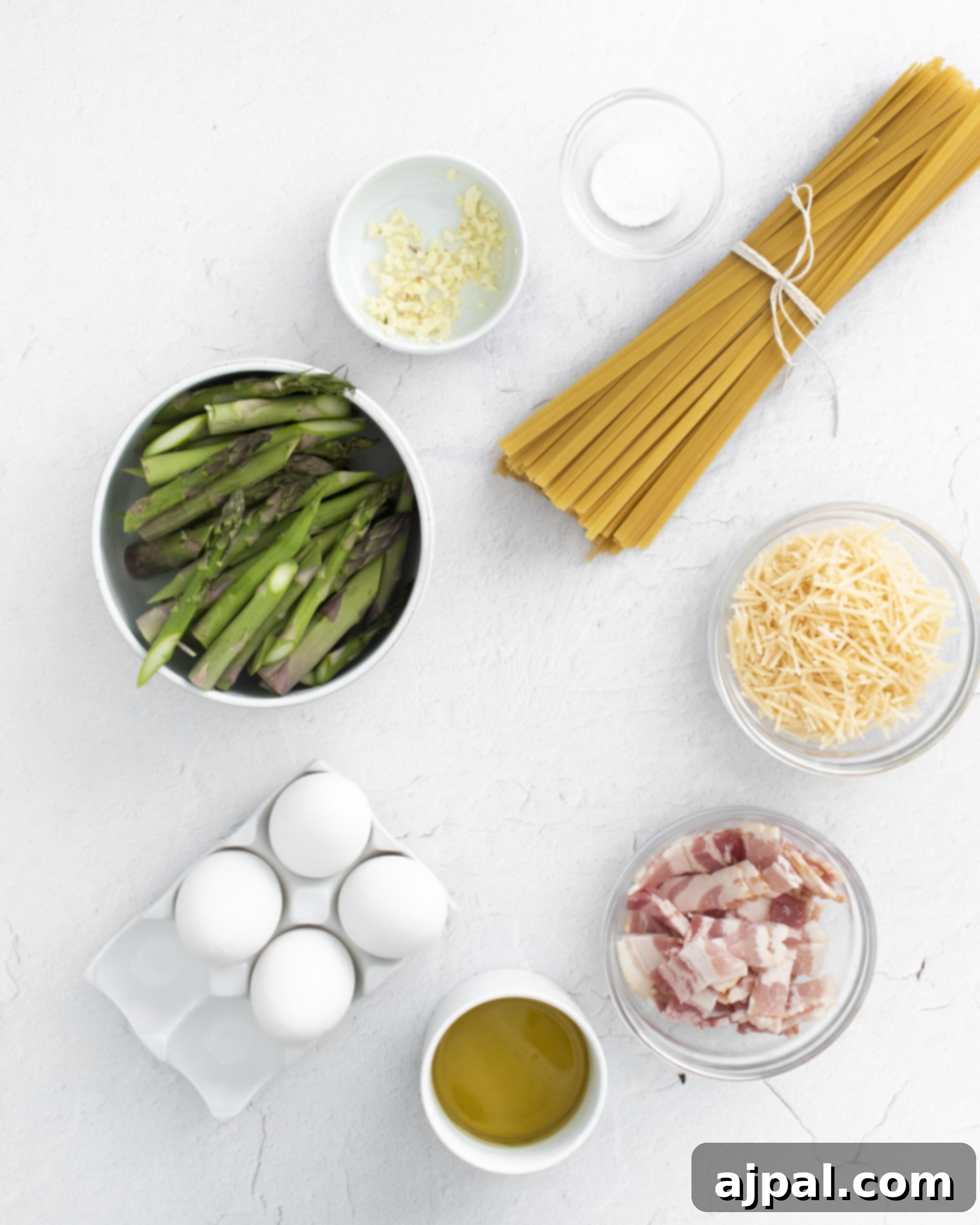Asparagus Carbonara with Roasted Flair 6 close-up picture of asparagus cheese egg bacon pasta and olive oil on a white wooden table