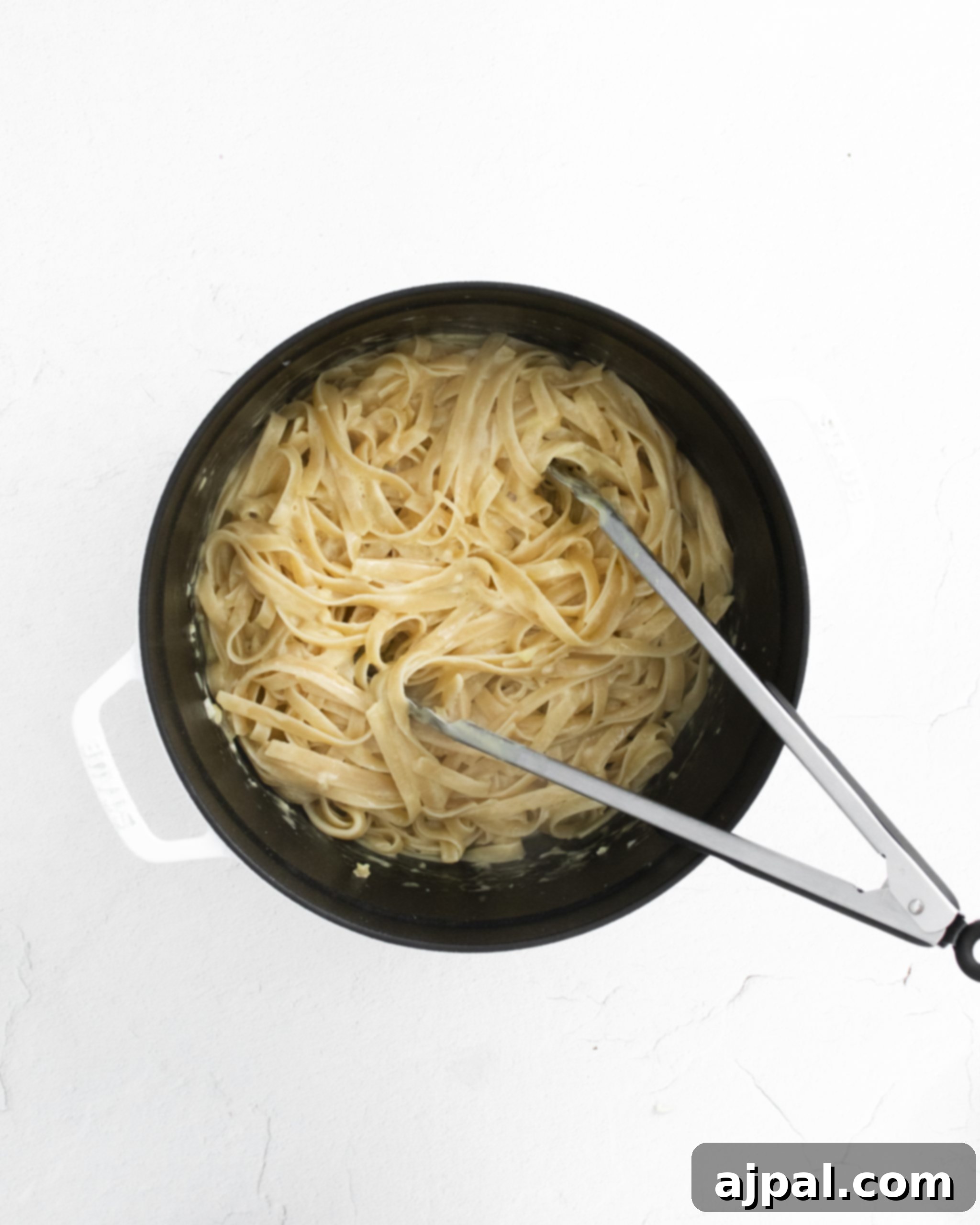 Asparagus Carbonara with Roasted Flair 12 picture of tongs mixing carbonara sauce into noodles in a large pot