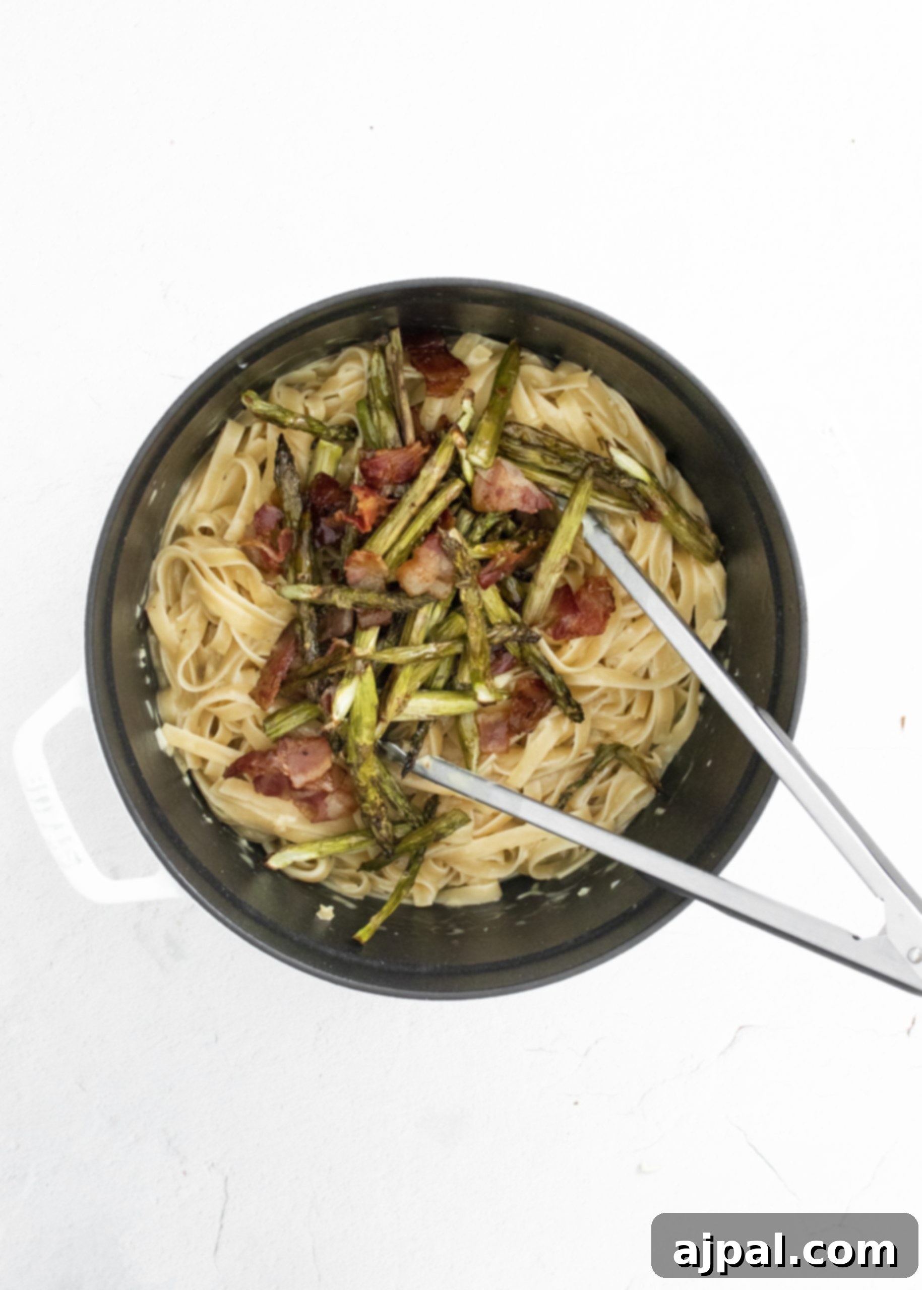 Asparagus Carbonara with Roasted Flair 13 picture of asparagus and bacon being stirred into carbonara pasta with tongs