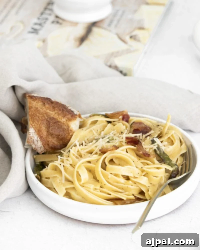 Asparagus Carbonara with Roasted Flair 4 A perfectly plated dish of creamy carbonara pasta with crispy bacon and roasted asparagus, set on a dark, textured surface with a side of fresh herbs.