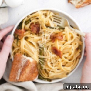 picture of hand holding bowl of asparagus carbonara pasta