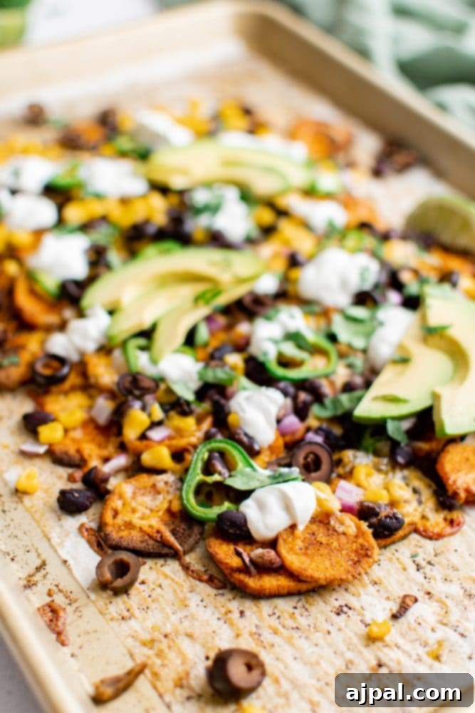 Sheet pan of vegetarian sweet potato nachos, perfectly baked with melted cheese and ready for fresh garnishes.