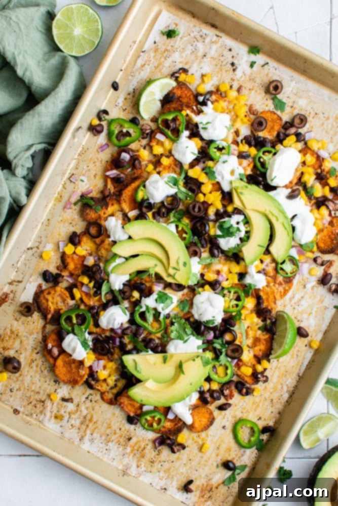 Sweet potato nachos recipe on a baking sheet, featuring a mouthwatering arrangement of toppings ready for baking.
