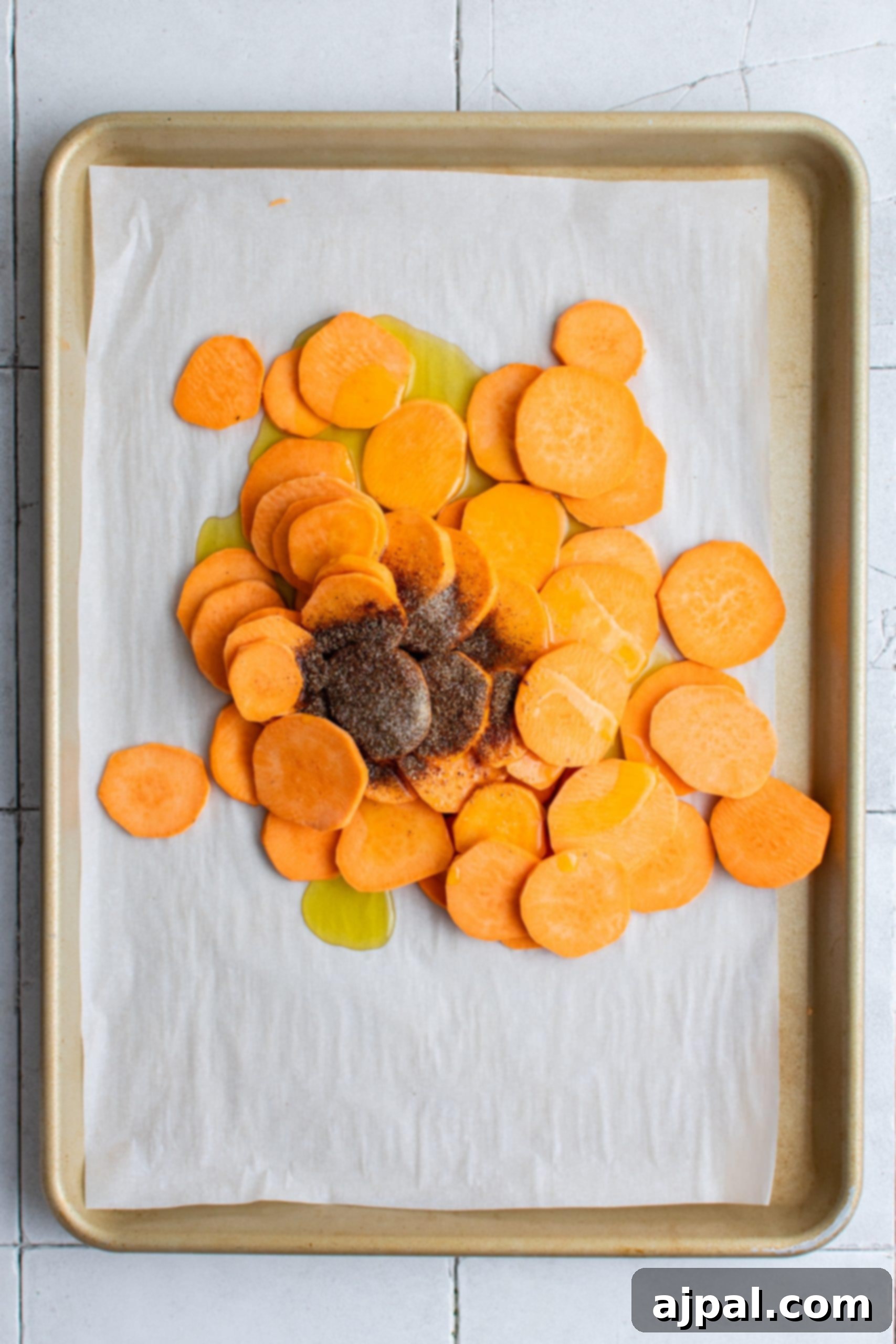 Thinly sliced sweet potatoes arranged on a baking sheet, seasoned and ready for baking into crispy chips for nachos.