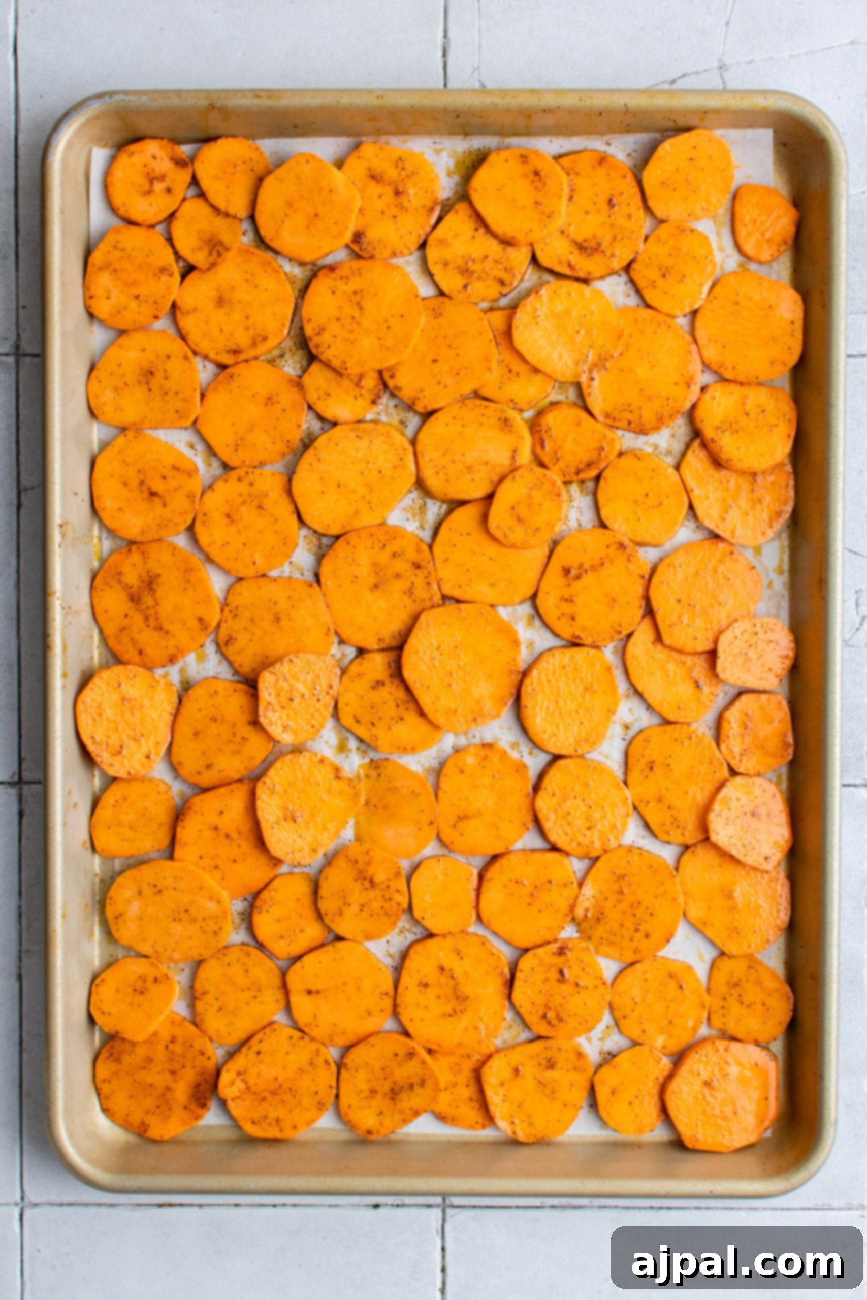 A closer look at the seasoned sweet potato chips, perfectly spaced on a baking sheet to ensure maximum crispiness.