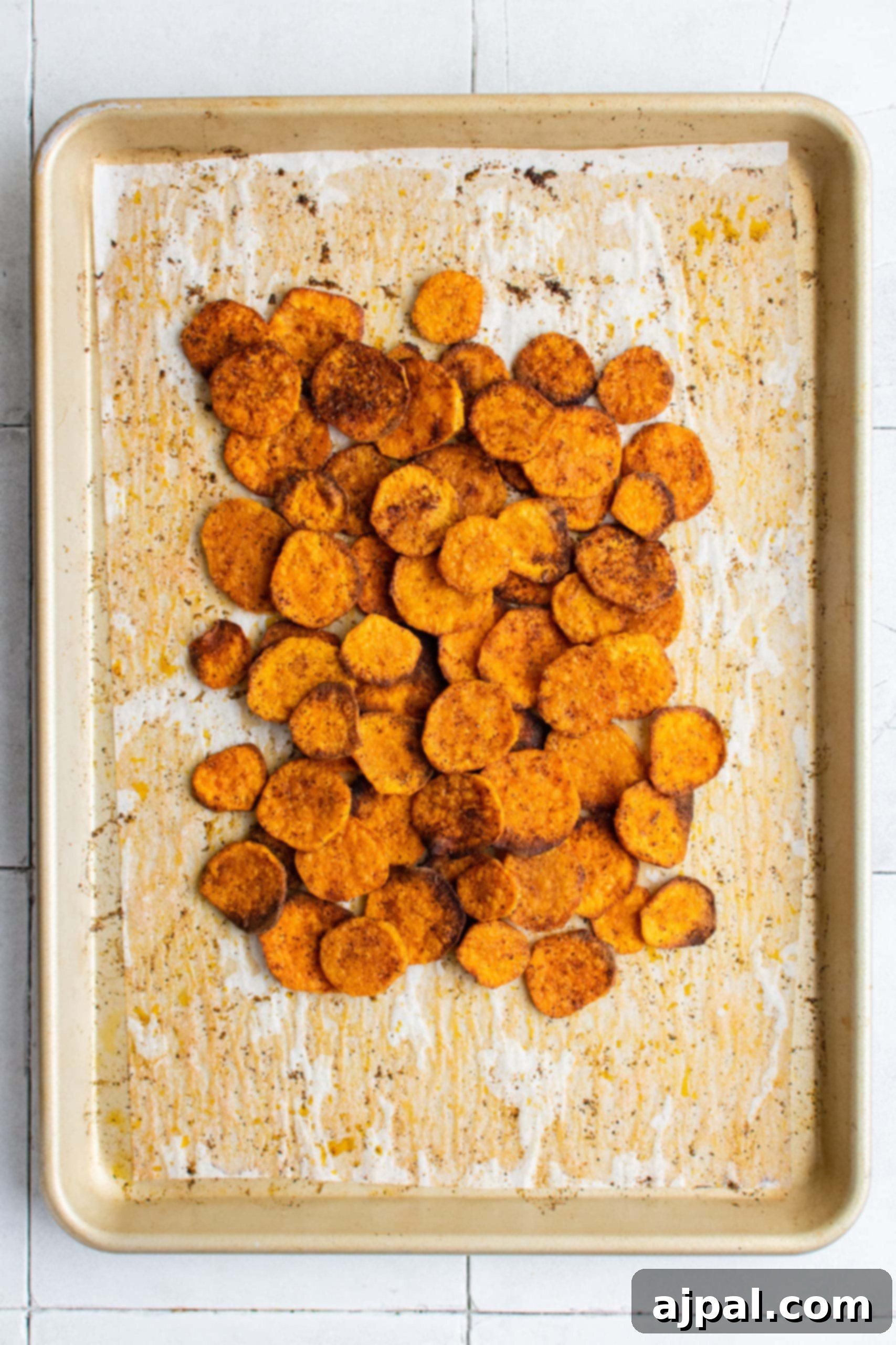 Sweet potato chips baking on a sheet, developing a golden brown and crispy texture.