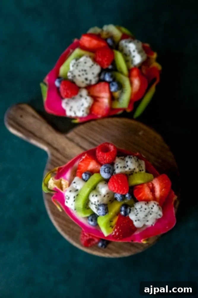 Tropical Dragon Fruit Salad 3 Picture of a vibrant dragon fruit salad artfully arranged on a wooden cutting board, showcasing a mix of tropical fruits and berries.