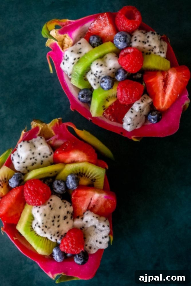 Tropical Dragon Fruit Salad 5 Picture of two dragon fruit halves, expertly carved and filled with a colorful fruit and berry salad, ready for serving.