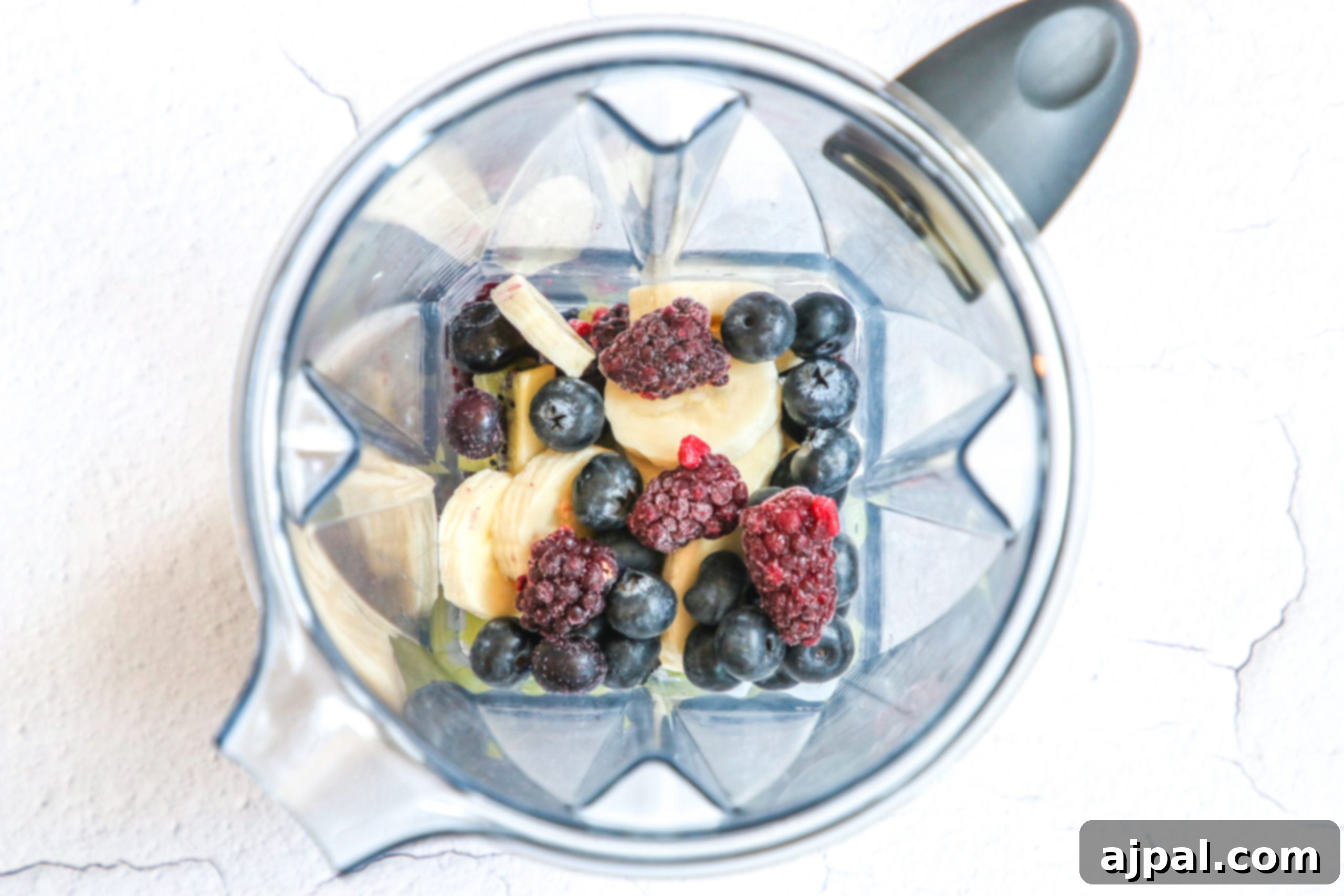 Triple Berry Smoothie Bowls 8 Inside a blender, a vibrant mix of frozen banana slices and assorted berries begins to meld, forming the rich base for a triple berry smoothie bowl.
