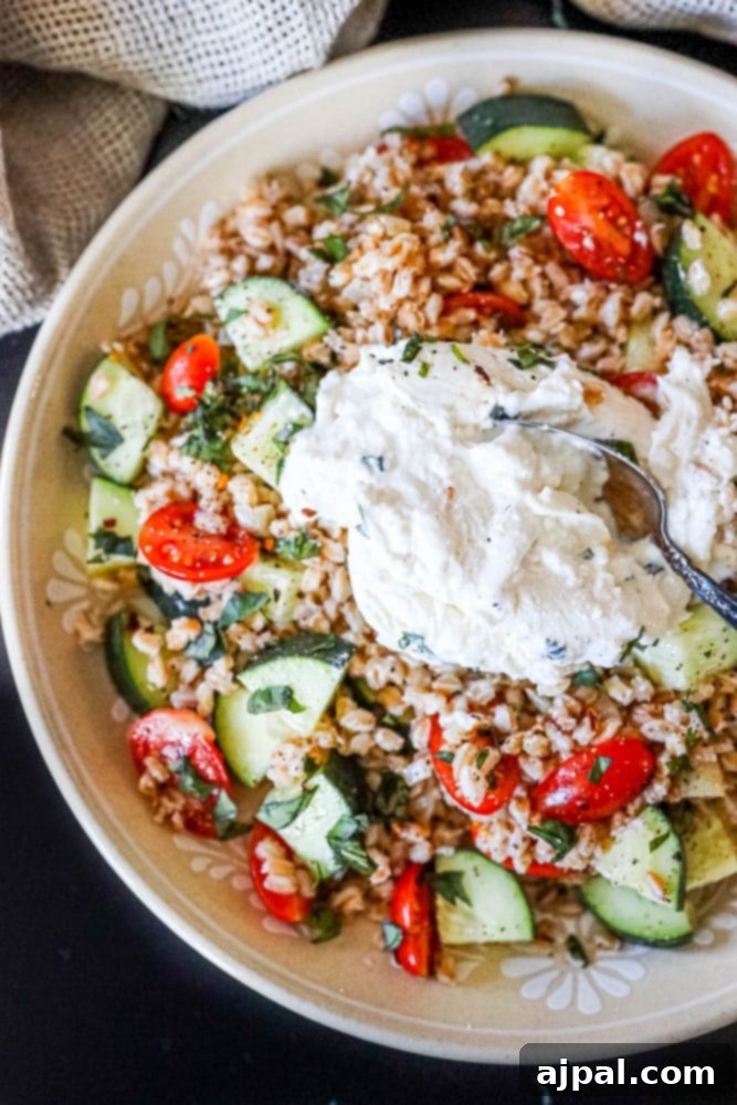A stunning overhead view of burrata farro salad, with creamy burrata perfectly split to reveal its rich interior, amidst vibrant fresh vegetables.