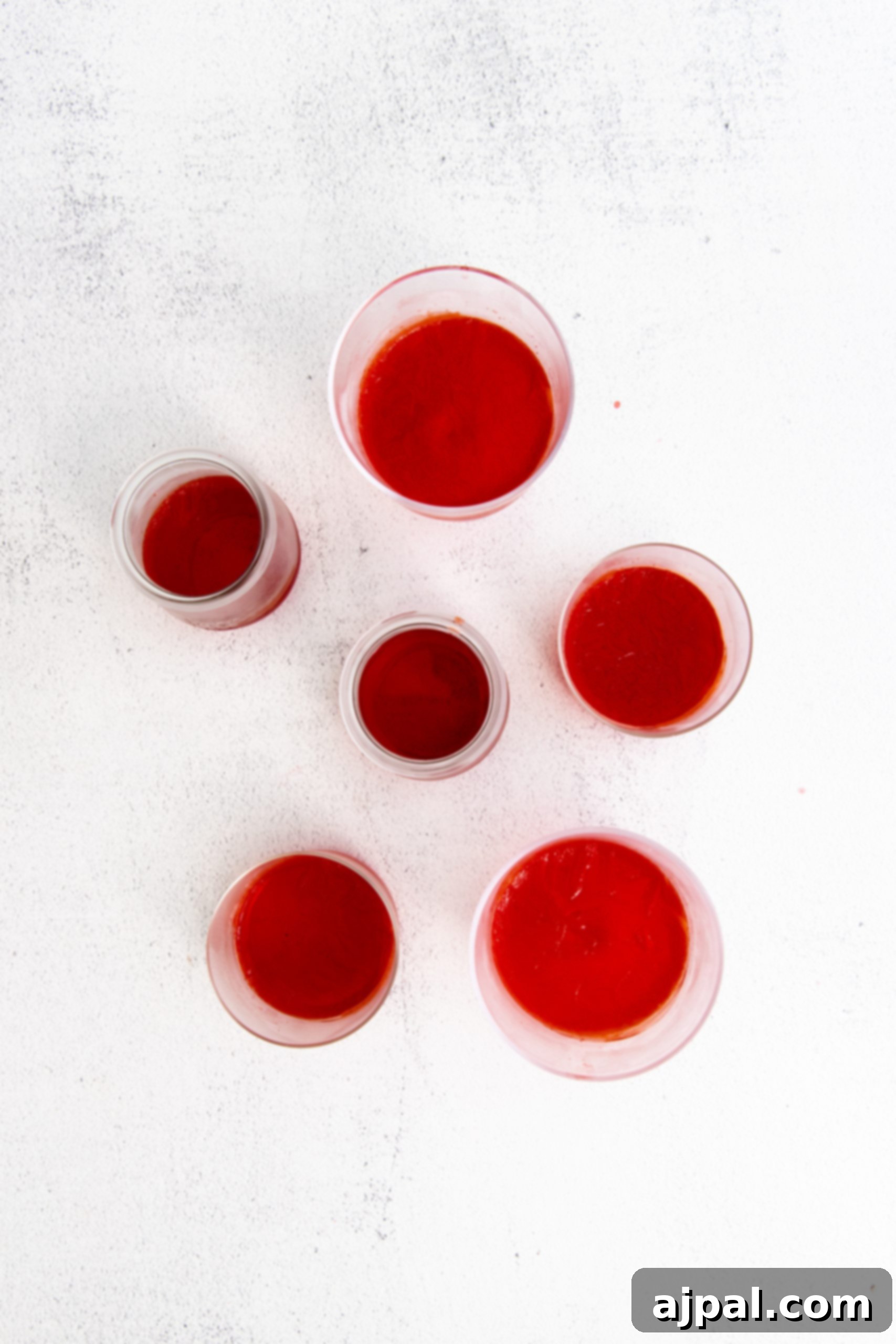 Star-Spangled Jello Cups 8 Five small bowls of red liquid on a white surface, perfect for a Fourth of July jello recipe.