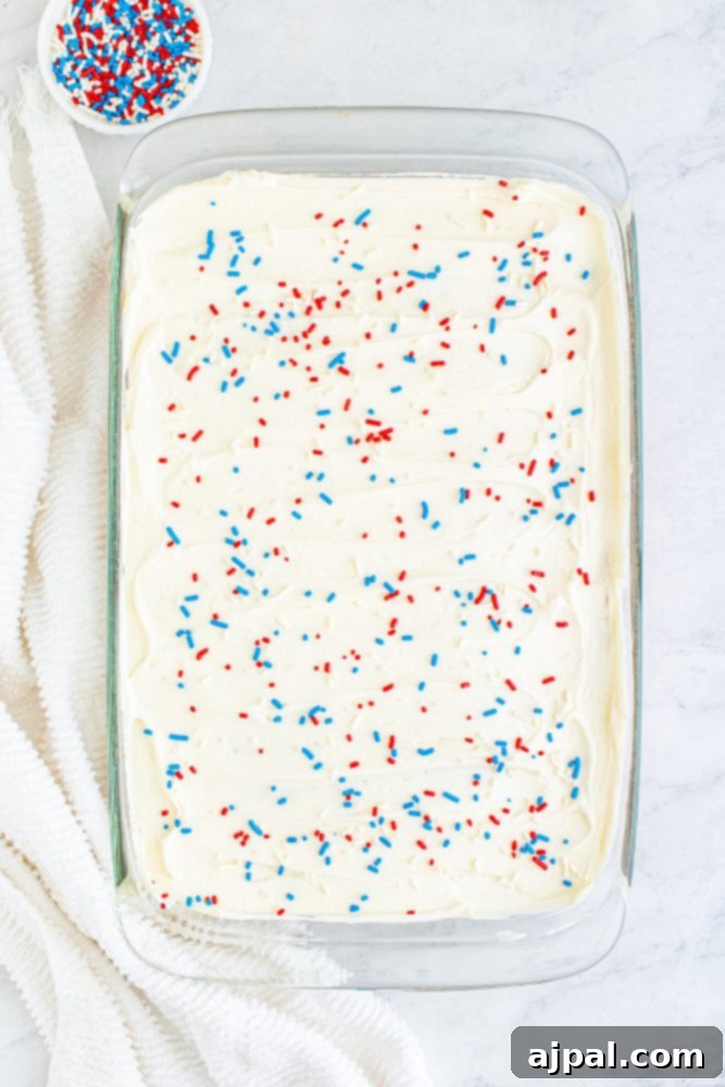 red white and blue sprinkles over iced sheetcake in a pan