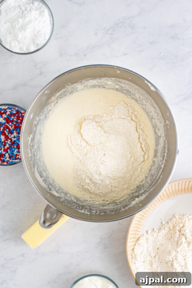 picture of flour dumped over wet cake ingredients in a bowl