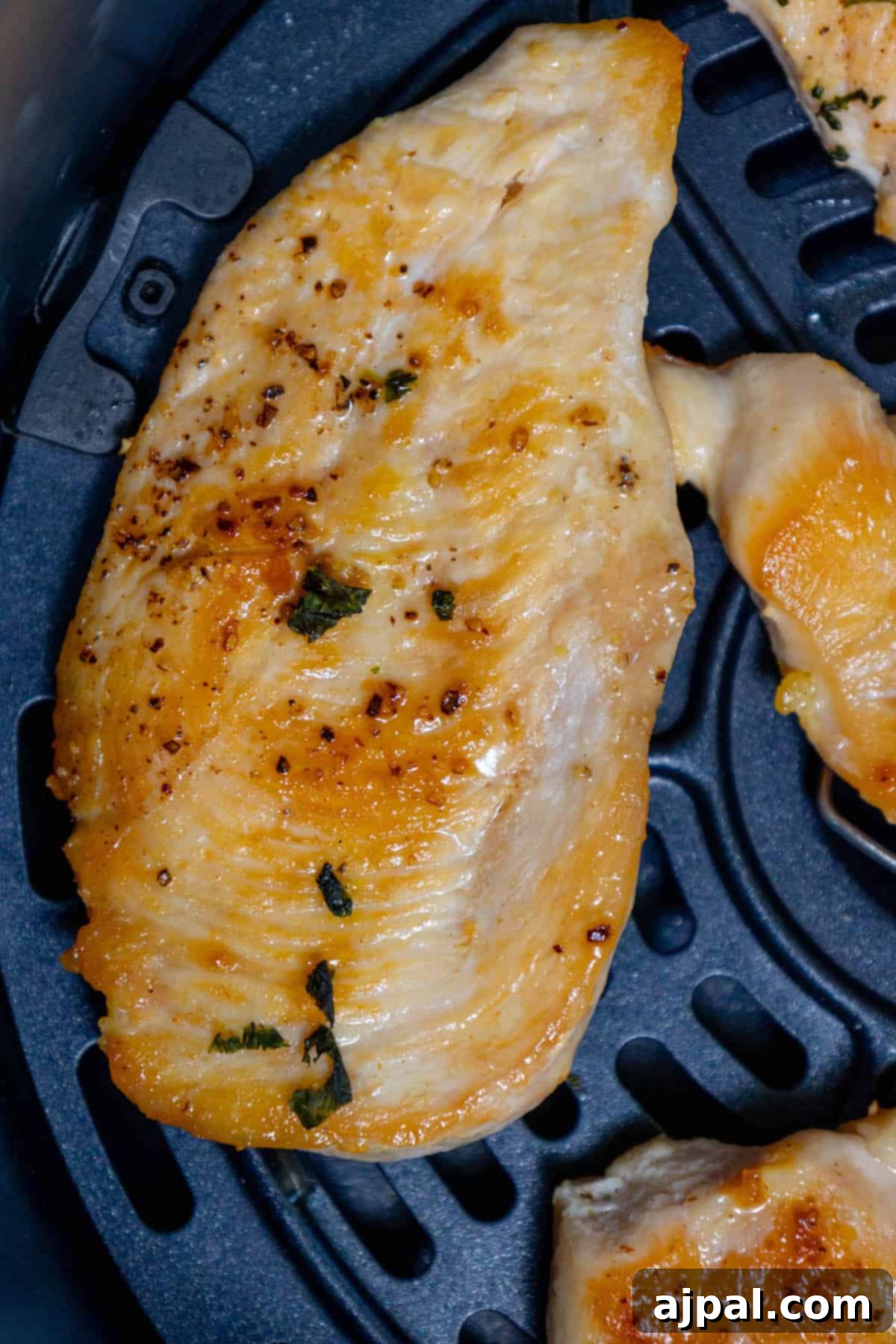 Keto air fried chicken breasts are being cooked in an air fryer, golden and sizzling.