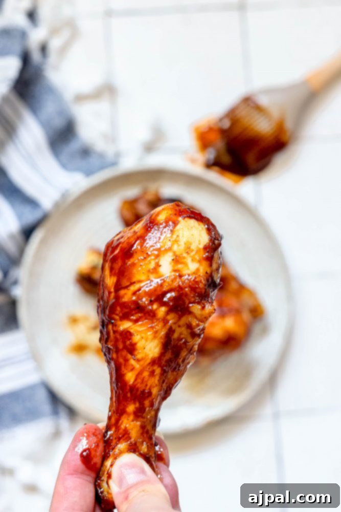 Ultimate Crispy Air Fryer BBQ Drumsticks 3 Close-up of a hand holding a perfectly air-fried BBQ chicken drumstick, covered in shiny sauce