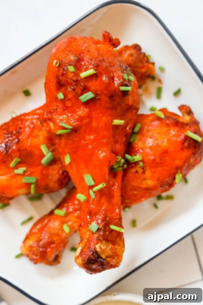Ultimate Crispy Buffalo Drumsticks 2 Golden-brown baked chicken drumsticks coated in fiery red buffalo sauce, ready to be served.