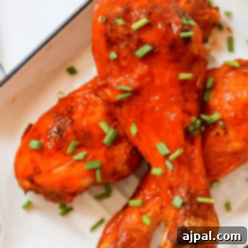 Ultimate Crispy Buffalo Drumsticks 11 Crunchy BBQ chicken legs on a plate with green onions.