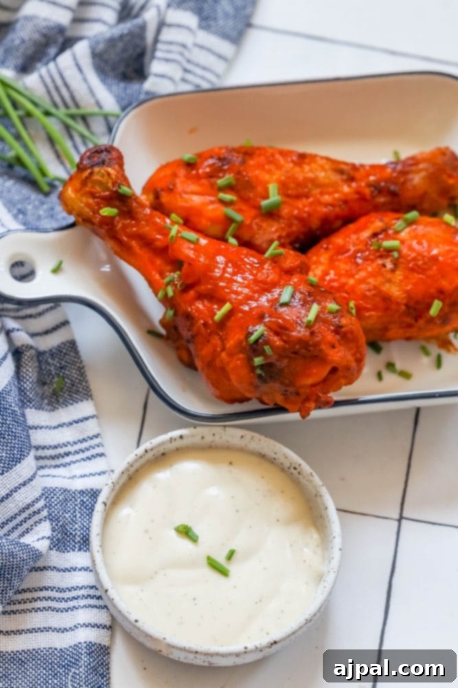 Ultimate Crispy Buffalo Drumsticks 8 A close-up of a single buffalo chicken drumstick on a plate, showcasing its crispy skin and rich sauce.