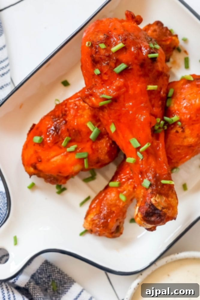 Ultimate Crispy Buffalo Drumsticks 9 A vibrant plate of buffalo chicken legs, garnished with fresh green onions and ready to be devoured.