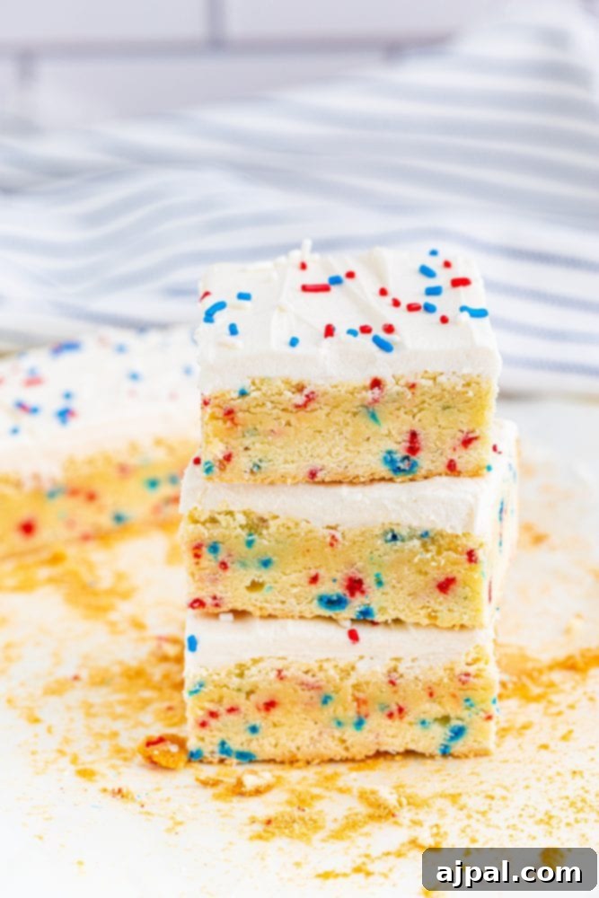 Stars and Stripes Sugar Cookie Bars 2 Three perfectly frosted vanilla sugar cookie bars adorned with patriotic red, white, and blue sprinkles, ready for a 4th of July celebration.