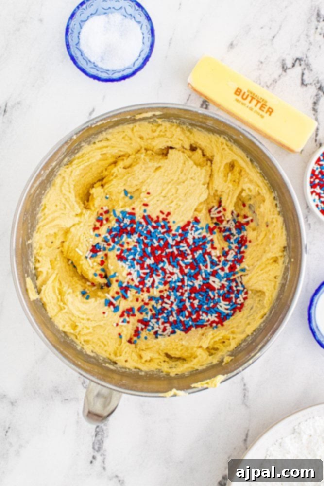 Stars and Stripes Sugar Cookie Bars 8 Vanilla cake batter in a mixing bowl, generously speckled with colorful sprinkles, ready for baking.