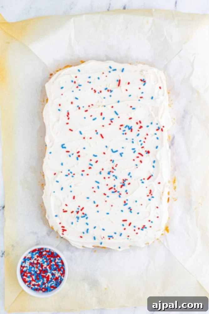 Stars and Stripes Sugar Cookie Bars 12 A large tray bake, generously covered in creamy white frosting and festive red, white, and blue sprinkles, perfect for a patriotic celebration.