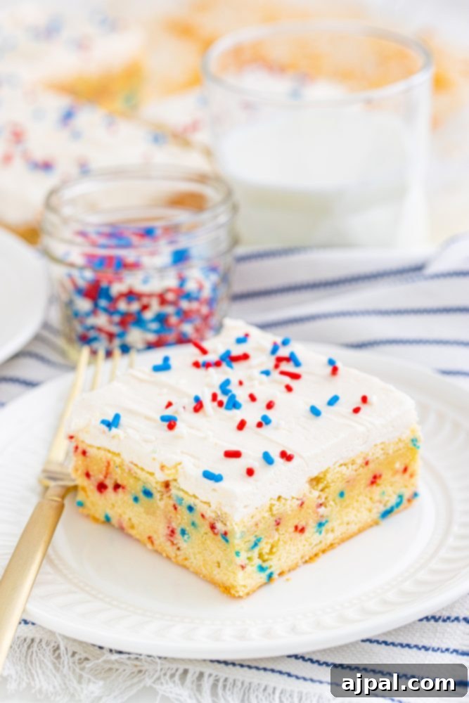 Stars and Stripes Sugar Cookie Bars 4 A close-up of a single patriotic sugar cookie bar, showcasing its thick, soft vanilla base, creamy frosting, and vibrant red, white, and blue sprinkles.