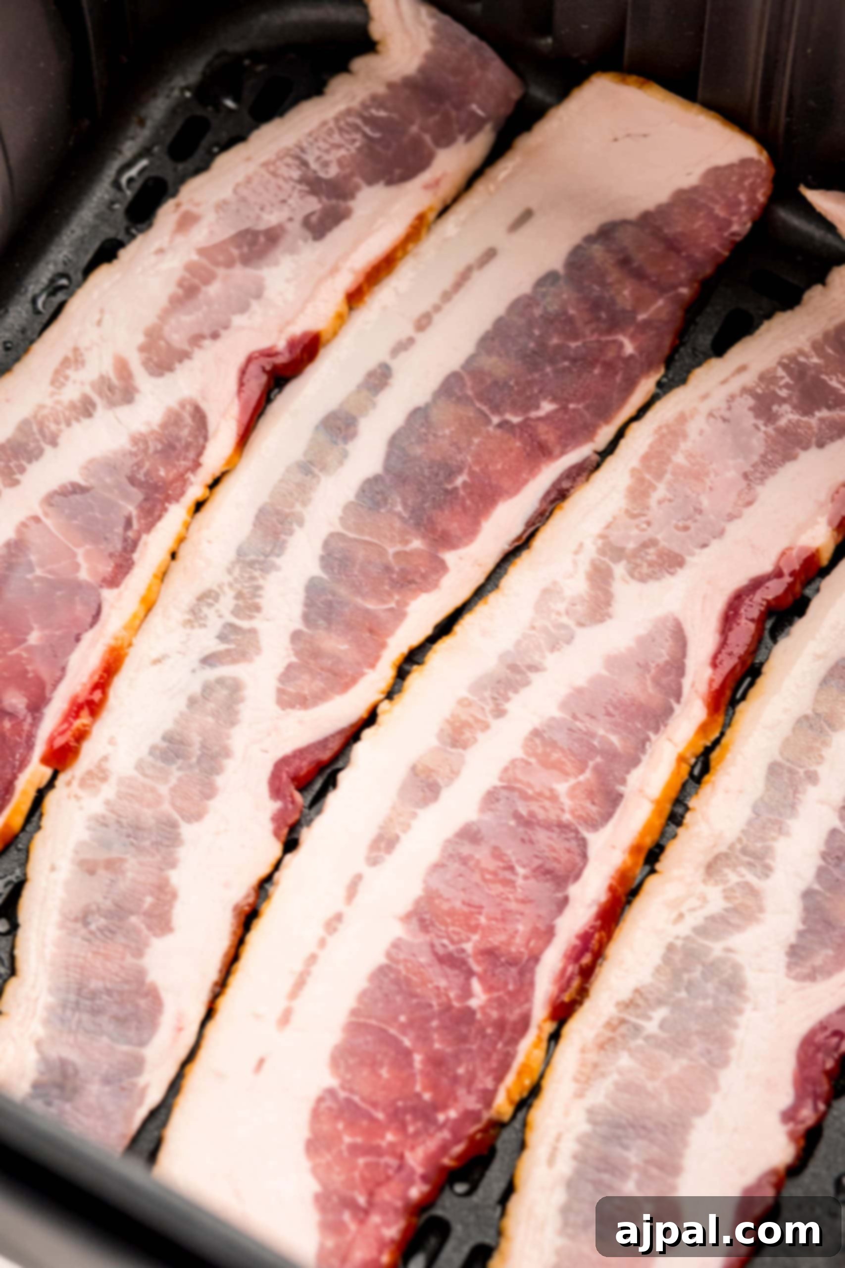 Close-up of raw bacon strips, showing their marbling and texture.
