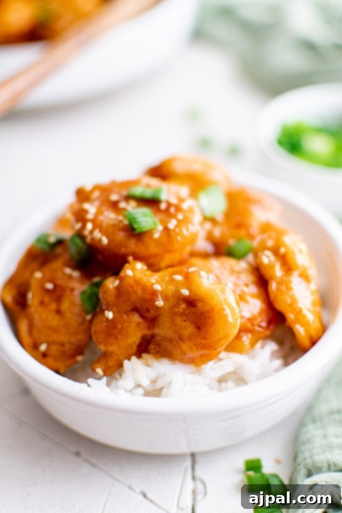 Effortless Sesame Chicken 4 picture of sesame chicken in a bowl over rice, garnished with fresh green onions