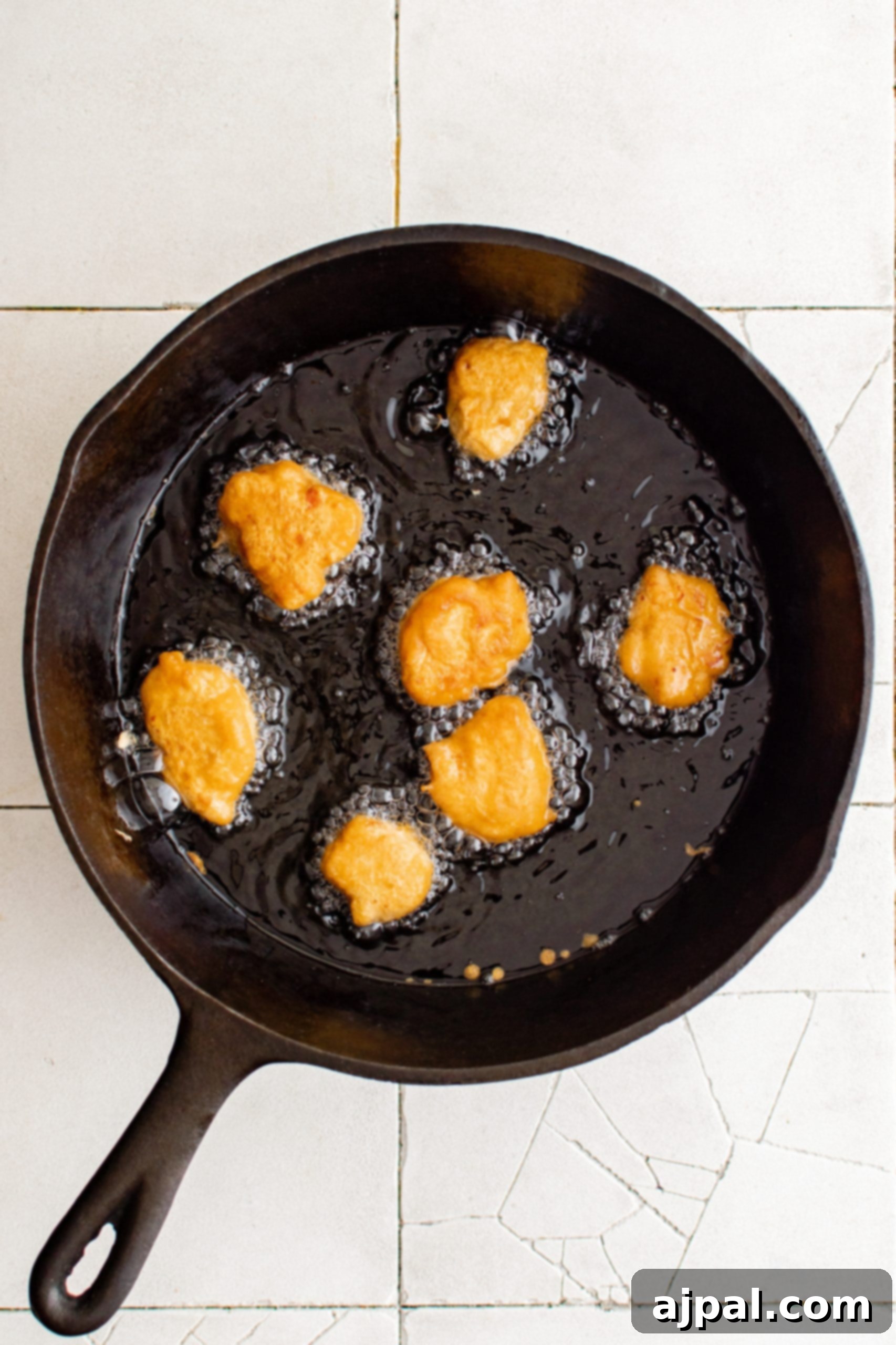 Effortless Sesame Chicken 7 Fried chicken breast pieces sizzling in a skillet, golden brown and perfectly cooked