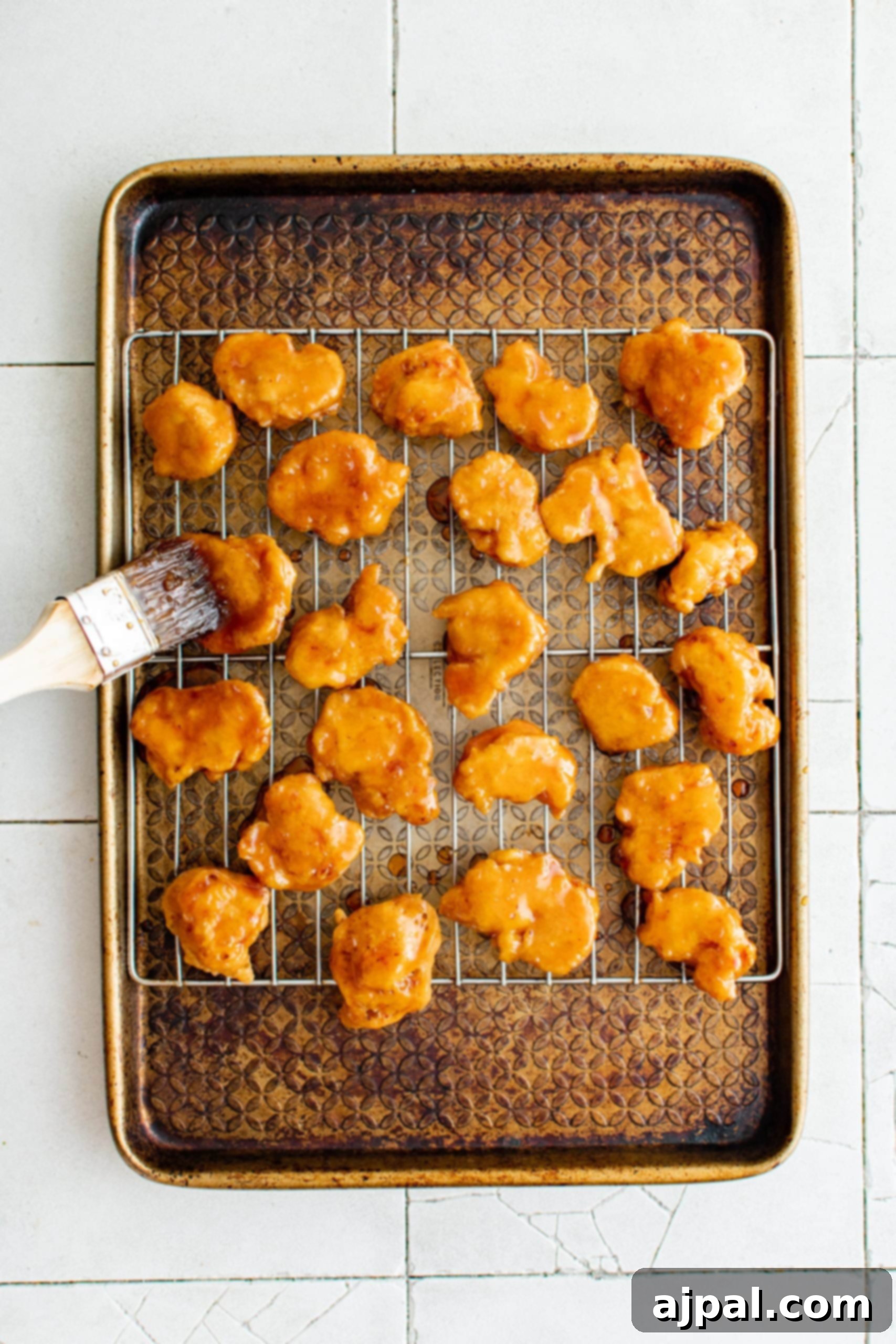 Effortless Sesame Chicken 8 A tray of easy sesame chicken on a baking sheet, freshly coated in sauce