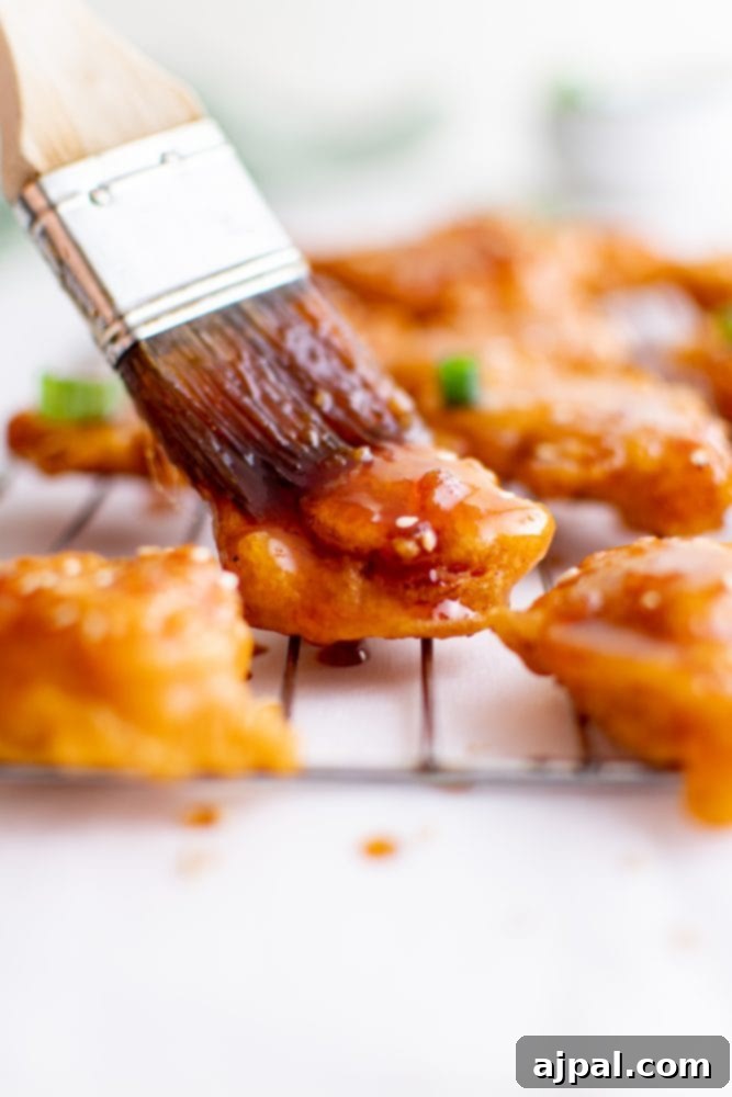 Effortless Sesame Chicken 9 picture of sesame chicken pieces being brushed with the sweet sticky sauce