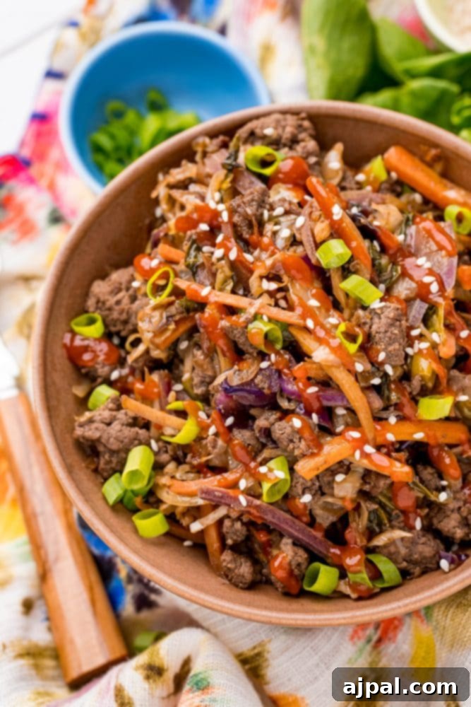 A beautifully presented bowl of low-carb egg roll stir-fry, featuring tender beef and noodles, resting on a rustic wooden table.
