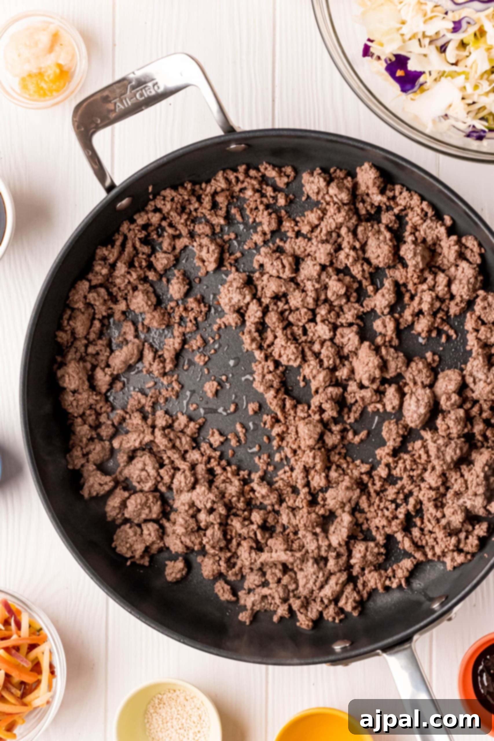 A keto egg roll in a bowl recipe featuring ground beef and other ingredients cooked in a frying pan.