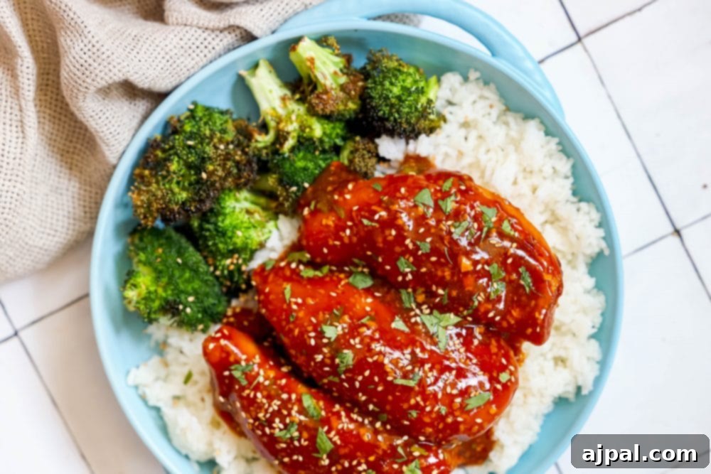 Sticky Honey Garlic Slow Cooker Chicken Breasts 6 A bowl of slow cooker honey garlic chicken with broccoli on a bed of rice, garnished with fresh sesame seeds.